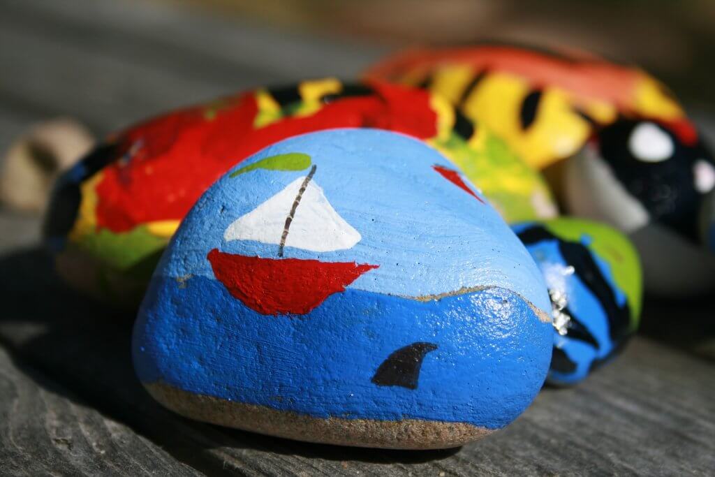 Colorful rock painted with a sailing boat